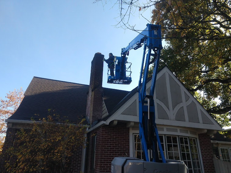 Worker on a mechanical lift, performing repairs on a chimney.